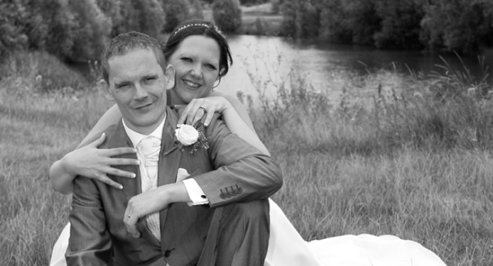 A bride and groom are posing for a picture in a field.