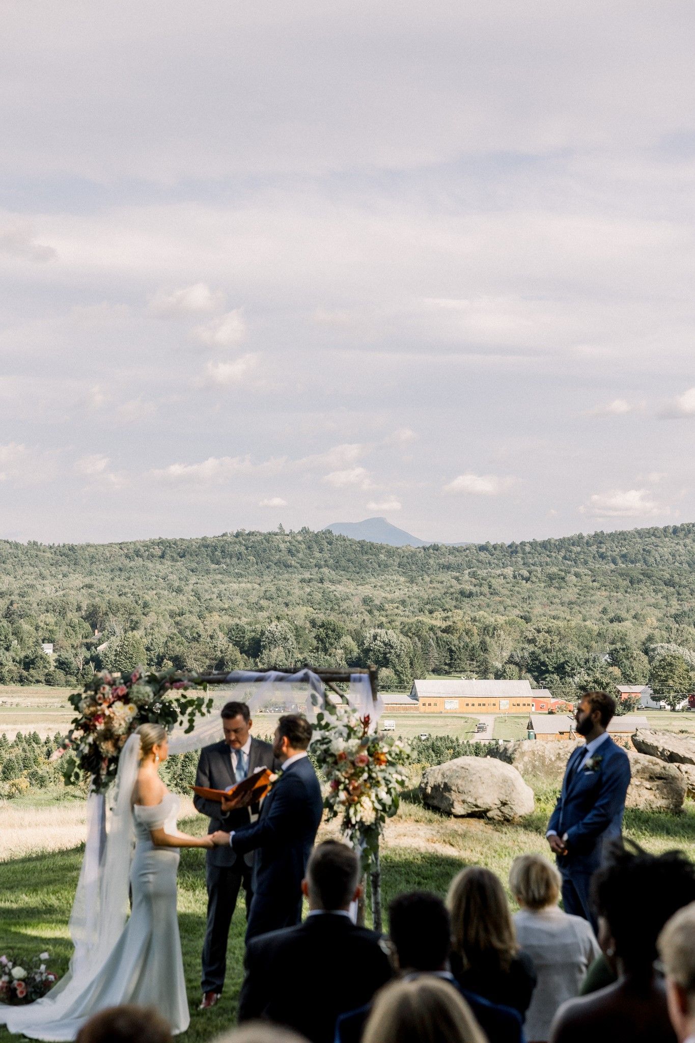 landscape shot of the trees sprawling out to the mountains at over a wedding ceremony set up at isham family farm in vt
