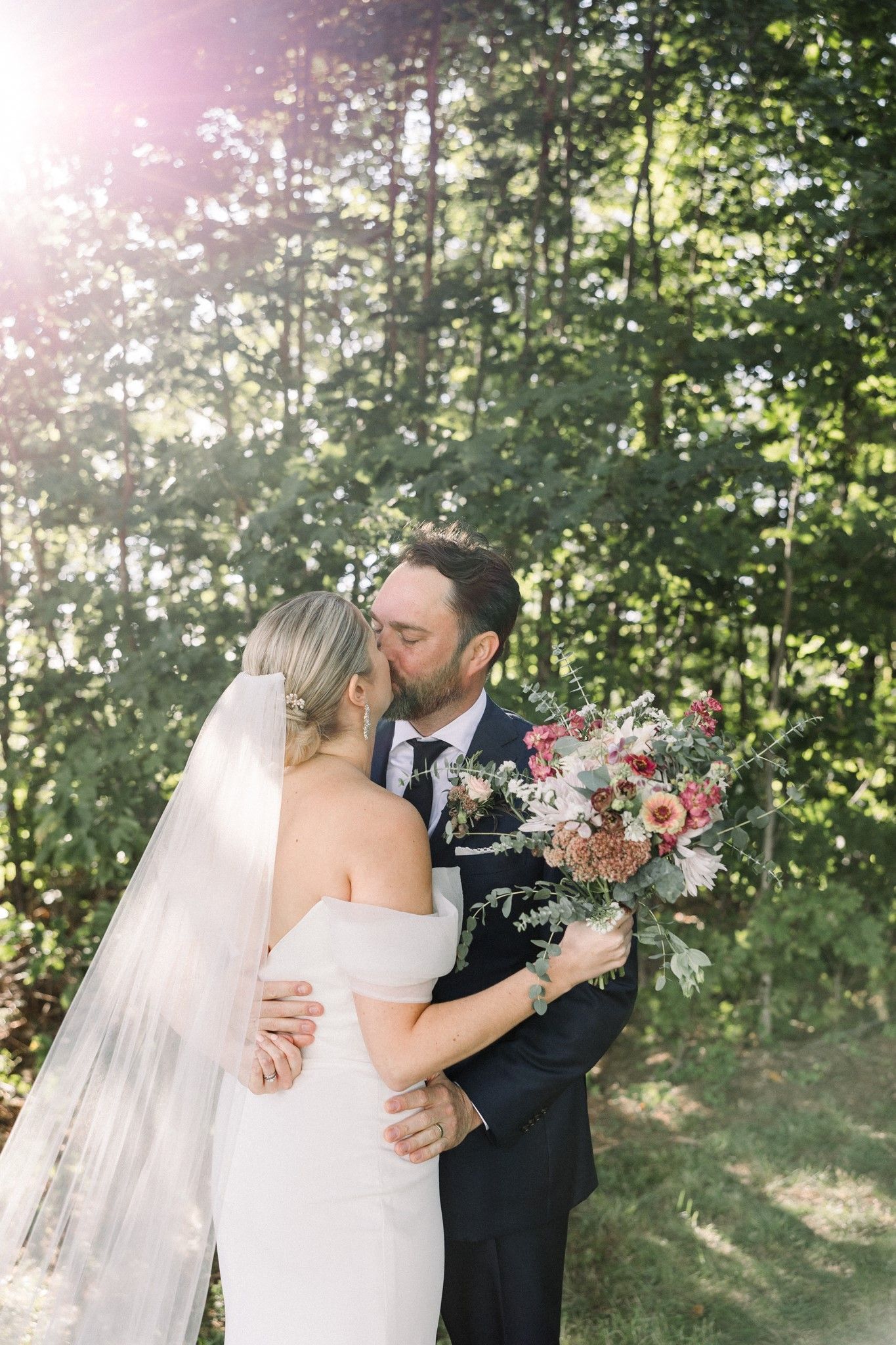 a bride and groom sharing their first kiss as a married couple just after their ceremony outside at isham family farm