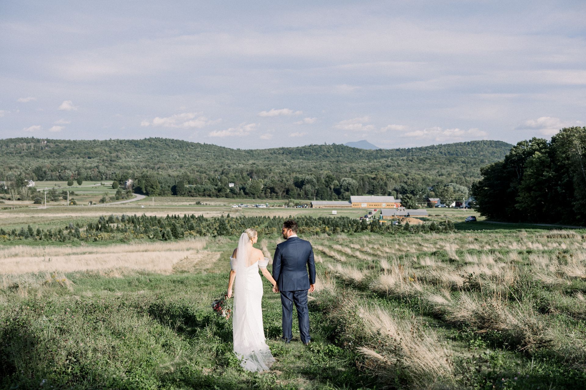 landscape photo of a couple from behind taking in the views of the mountains at isham family farm after their wedding.