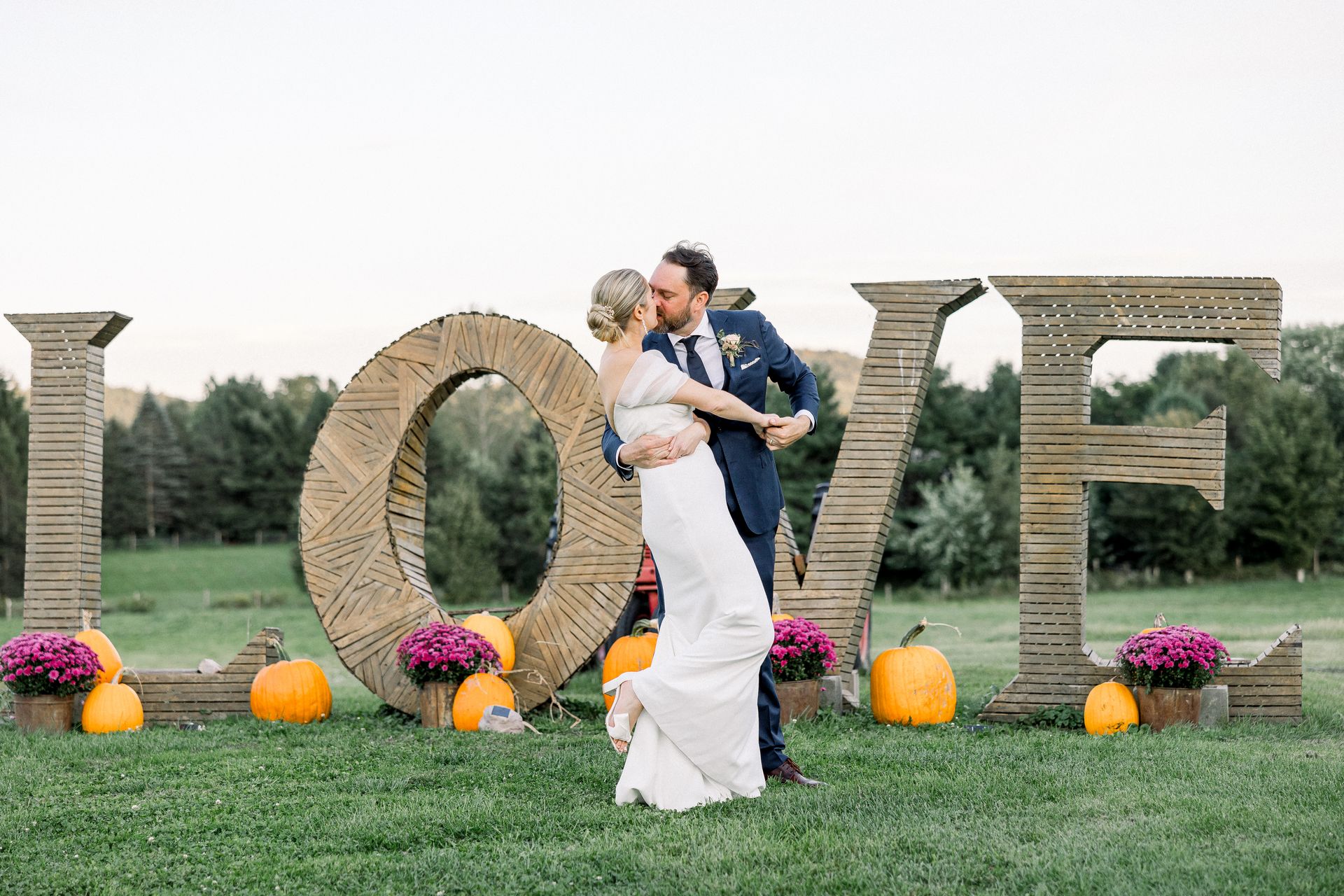 Just married couple kissing in front of wooden love sign at isham family farm