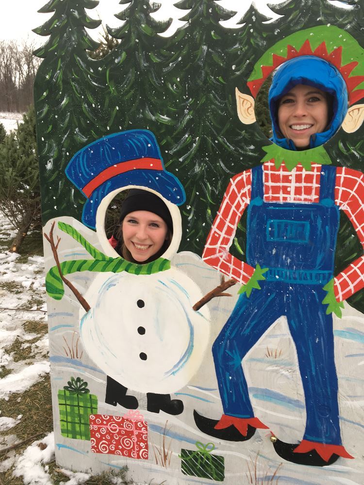 Siblings taking a photo as a snowman and farmer on a snowy day at isham family farm