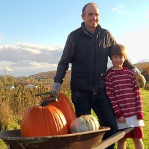 Father and son standing in front of isham family farm with their pumpkins with mountain views behind them