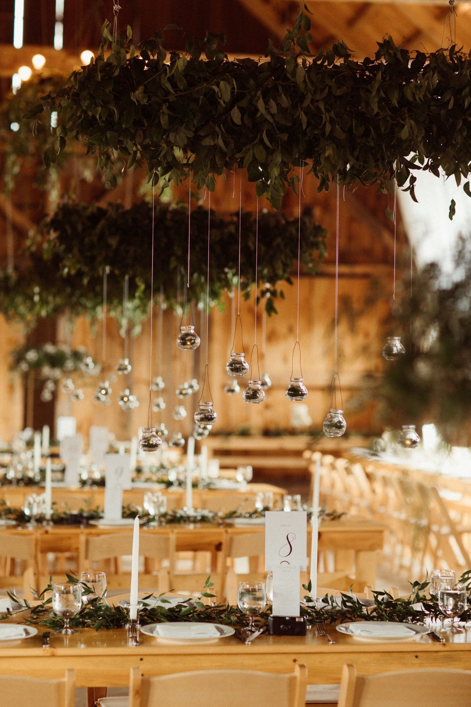 ornaments hanging from an evergreen display above the reception table at an isham family farm wedding