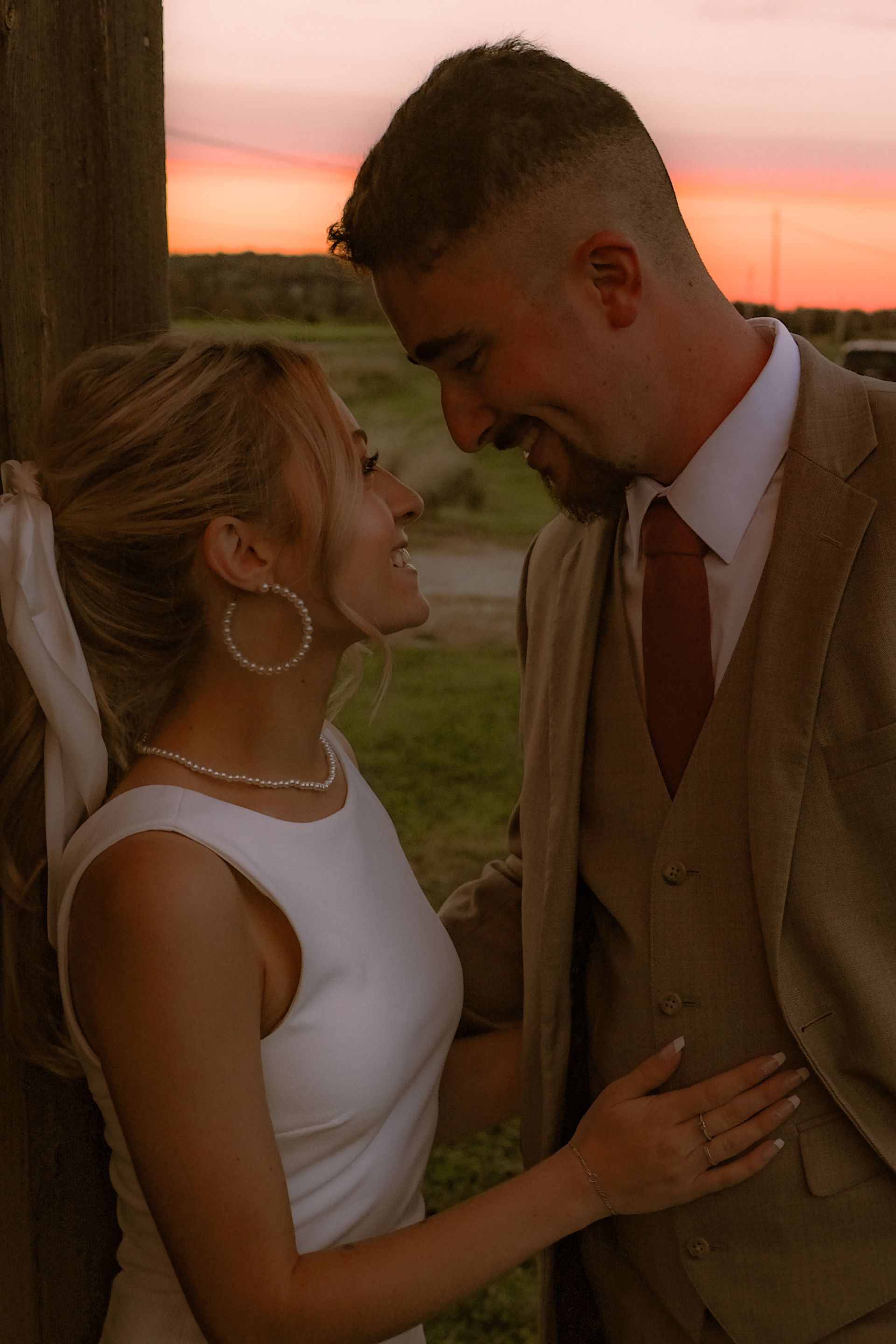 Bride and groom at golden hour on Isham Family Farm, sharing a quiet moment with sunset glow in the background.