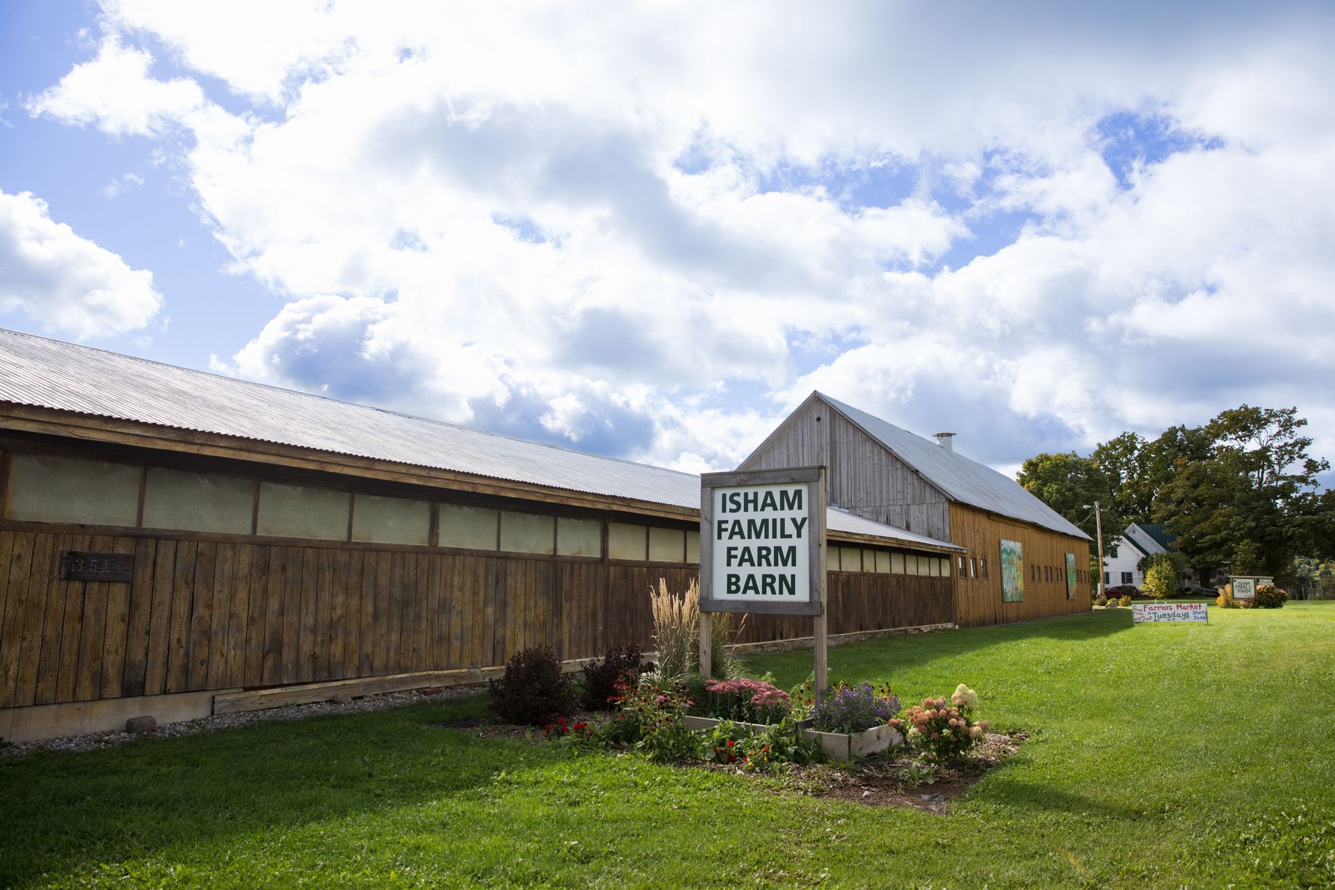 Landscape photo of the isham family farm chicken coop, in front there is a hand painted sign reading
