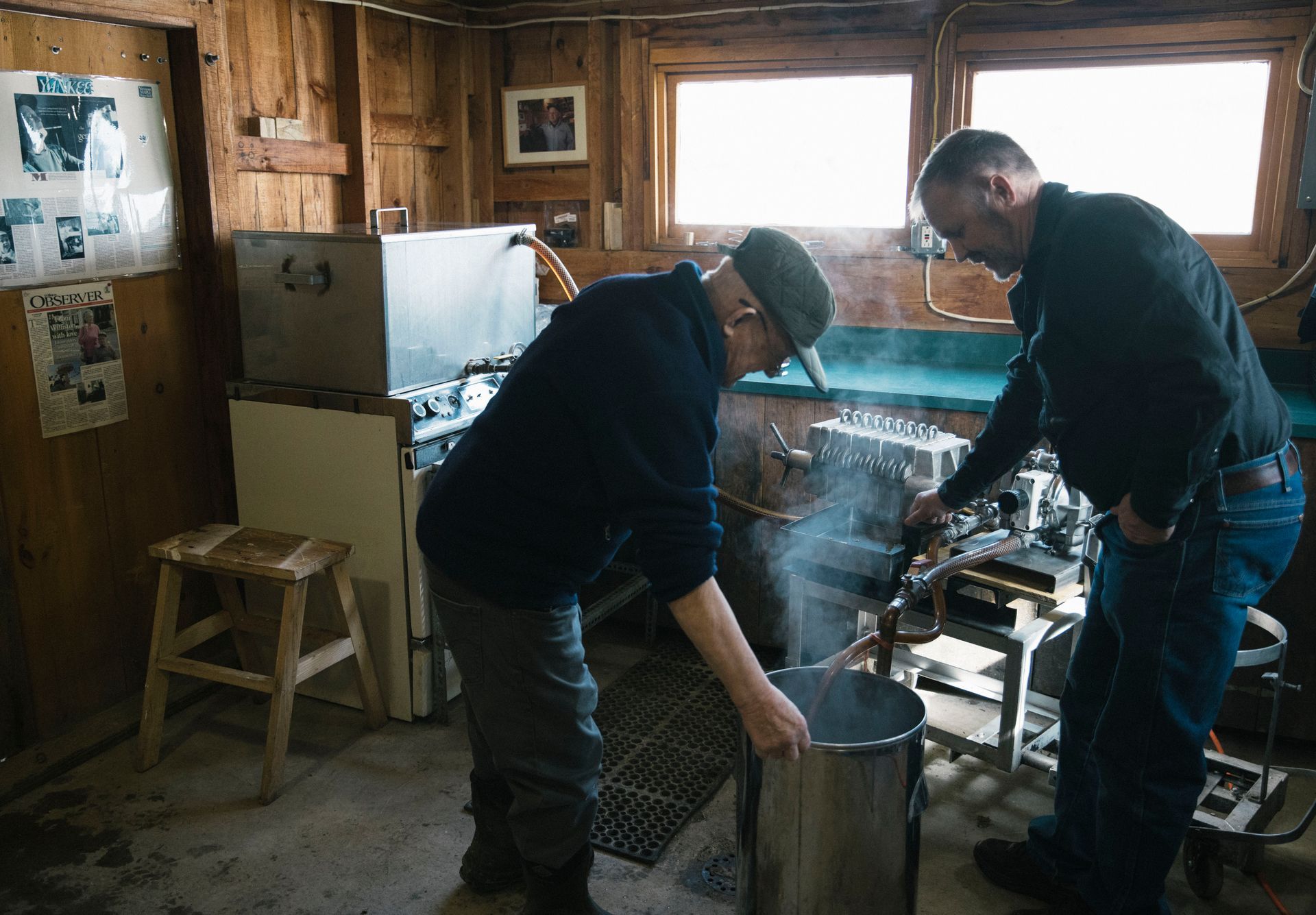 Sugarmakers filtering hot maple syrup into a stainless steel container at Isham Family Farm’s sugarhouse in Vermont.