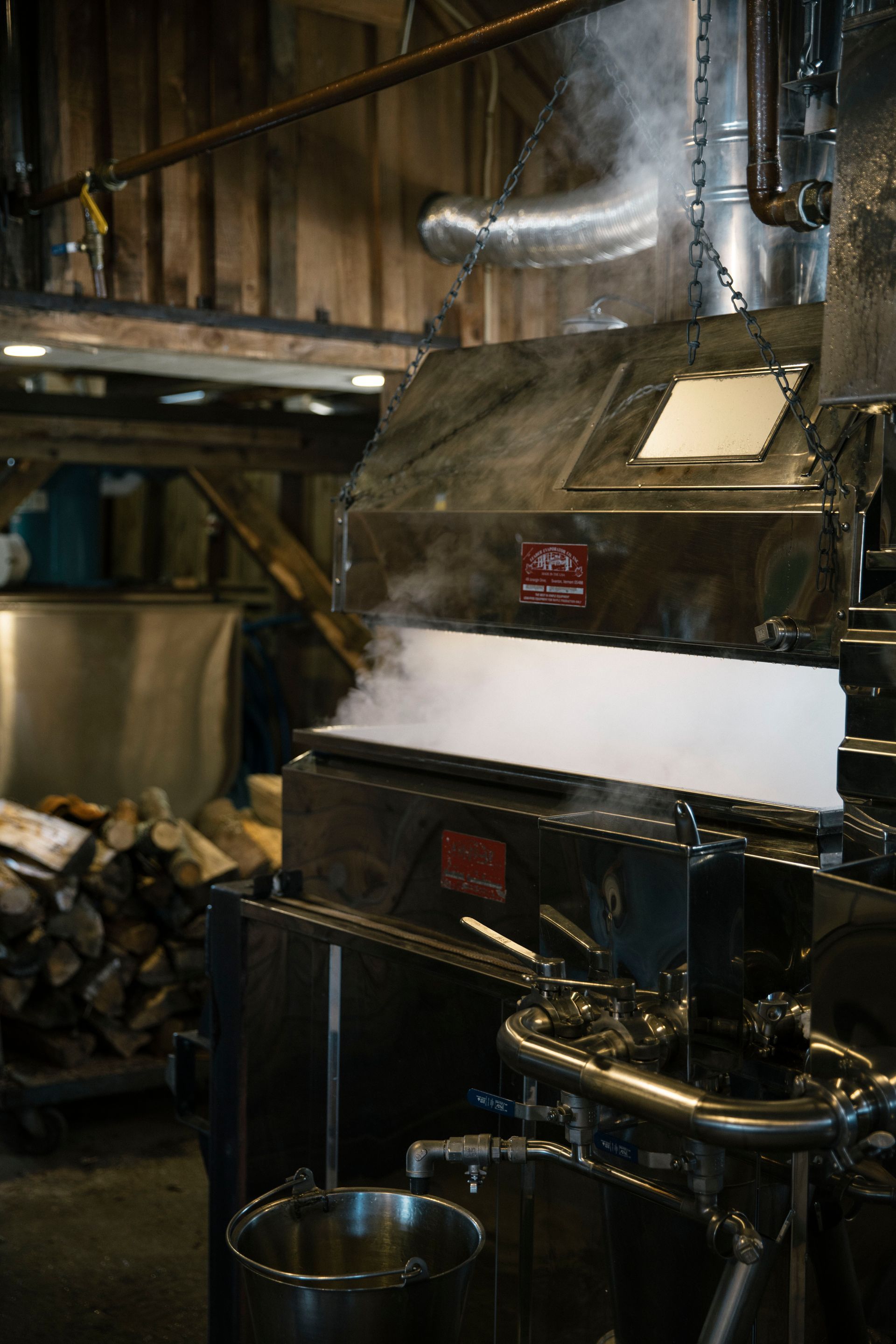 Steam rising from stainless steel maple syrup evaporator inside the sugarhouse at Isham Family Farm in Vermont.