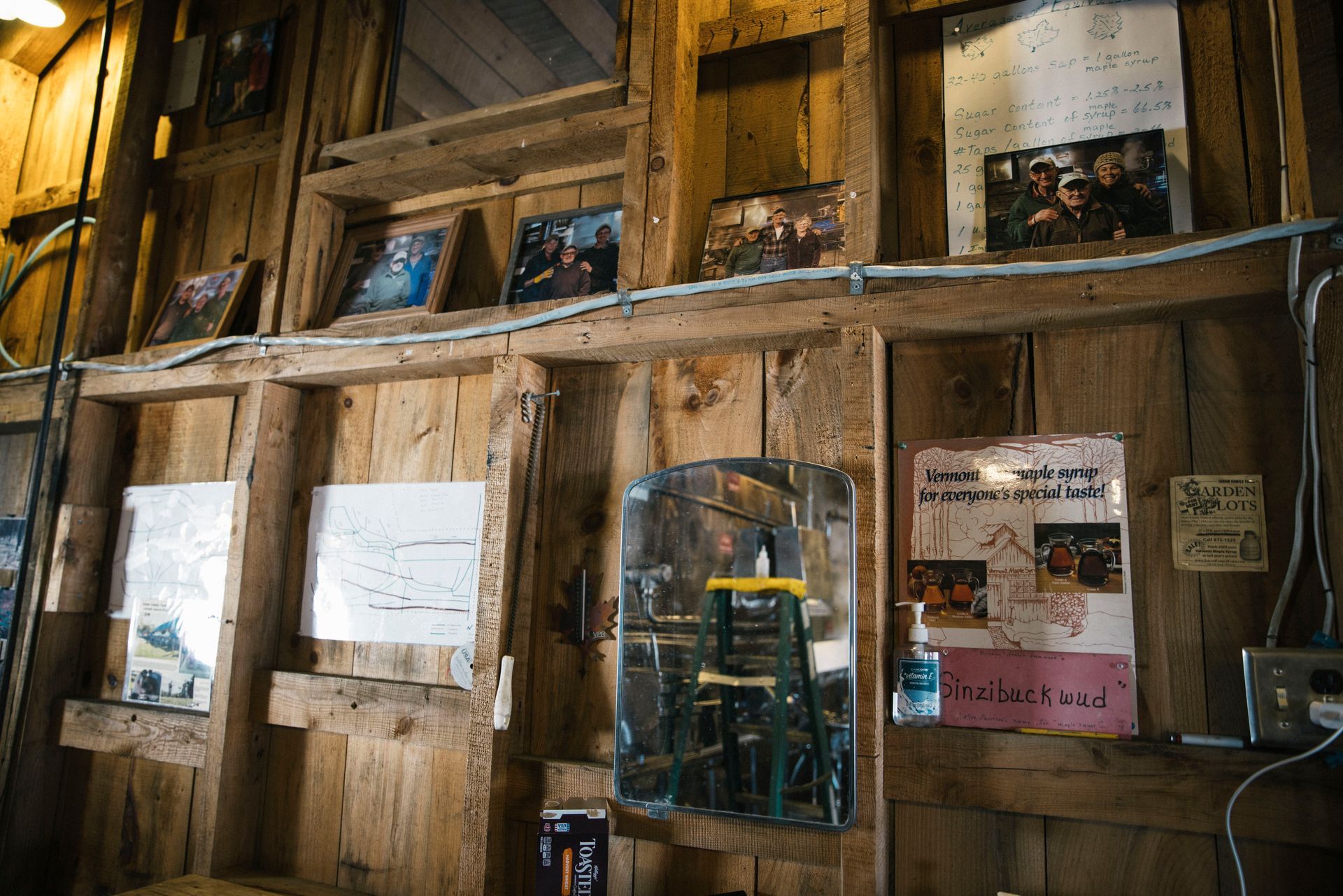 Wall of family photos, syrup production notes, and vintage Vermont maple syrup posters inside the sugarhouse
