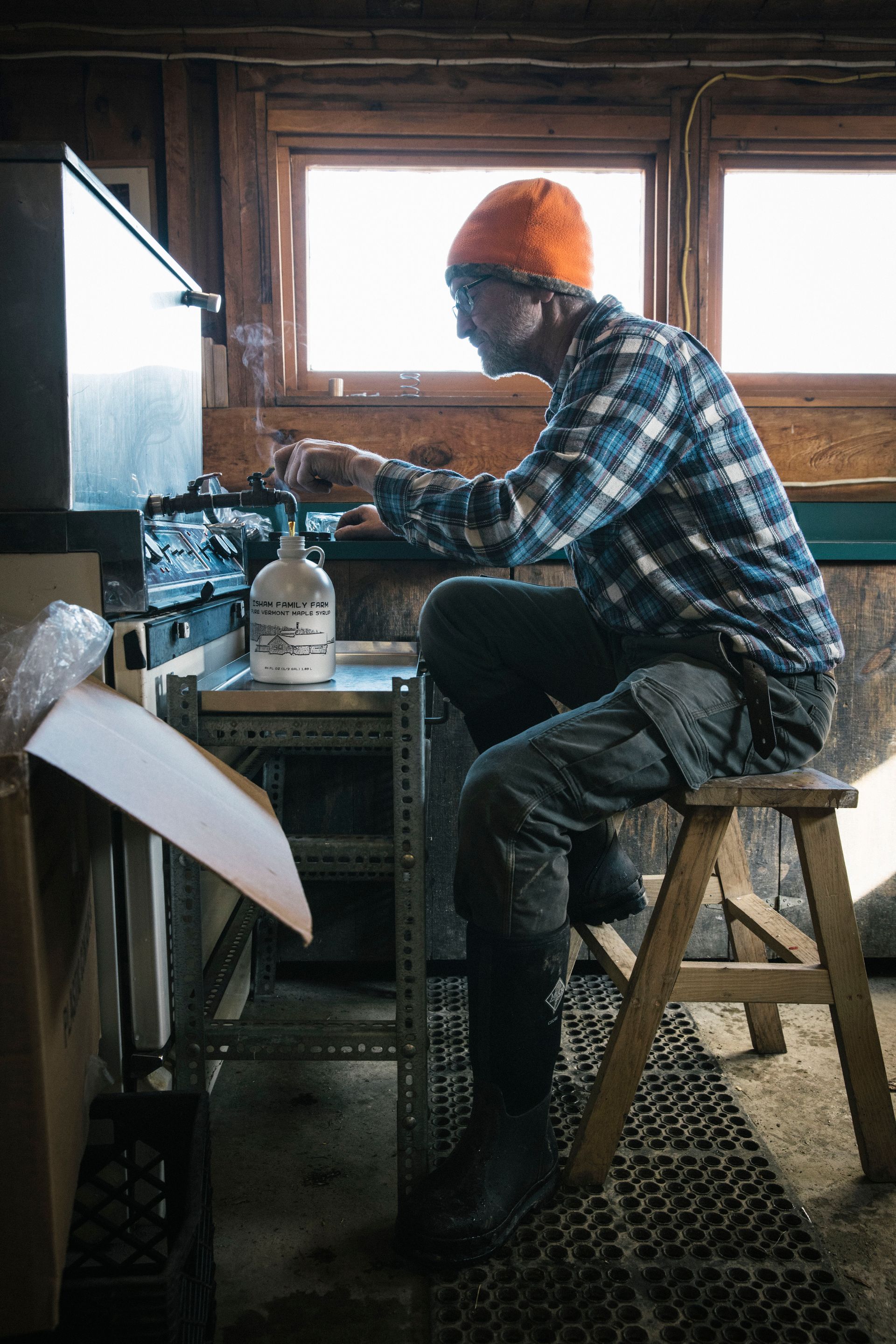 Man bottling fresh Vermont maple syrup at Isham Family Farm inside the sugarhouse.