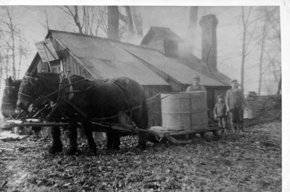 Vintage black and white photo of Isham Family Farm with 3 family members standing in front of the main house with two Clydesdale horses