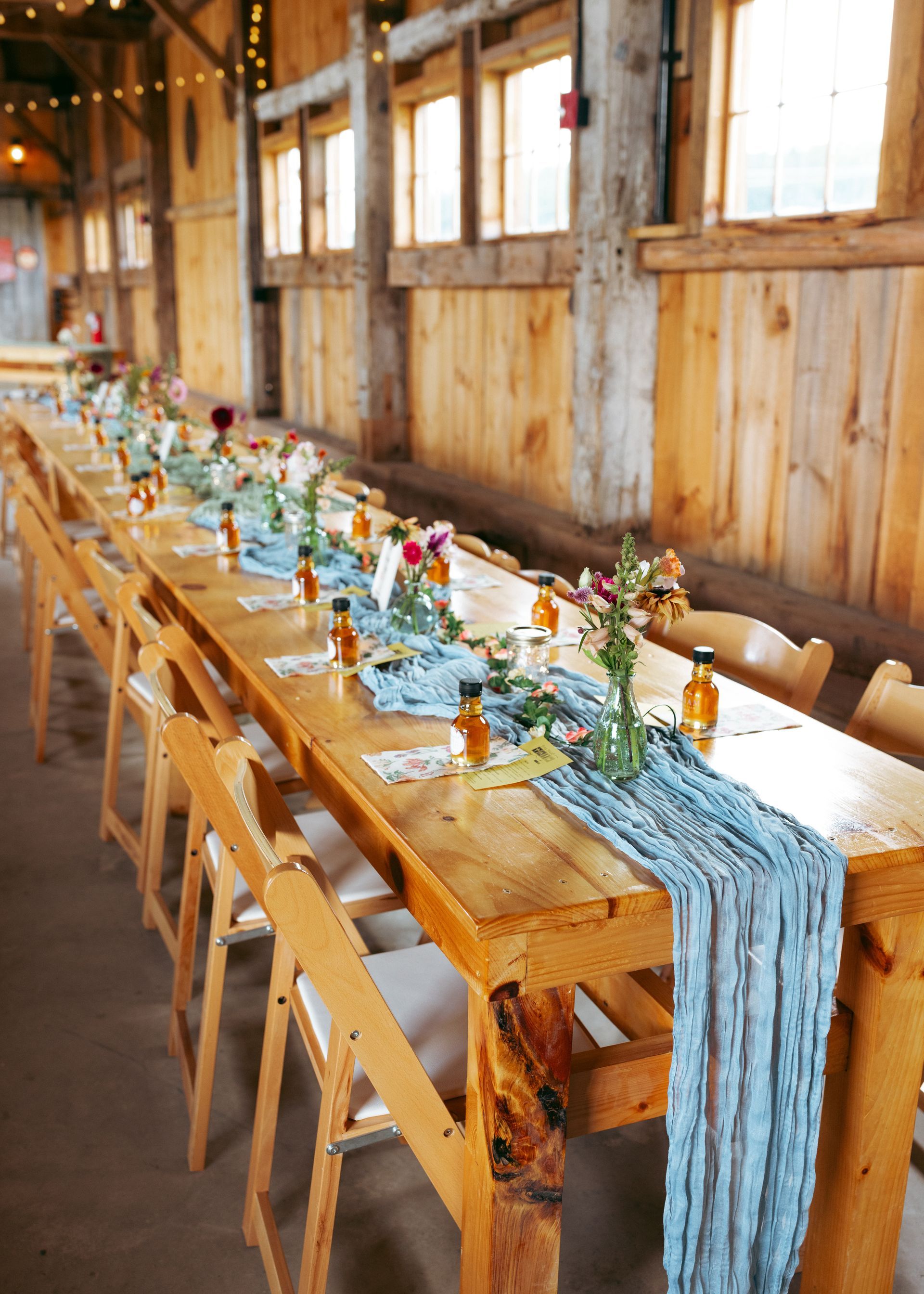 rustic wedding reception table display with linen runner and shots of local whiskey in the events barn at isham family farm