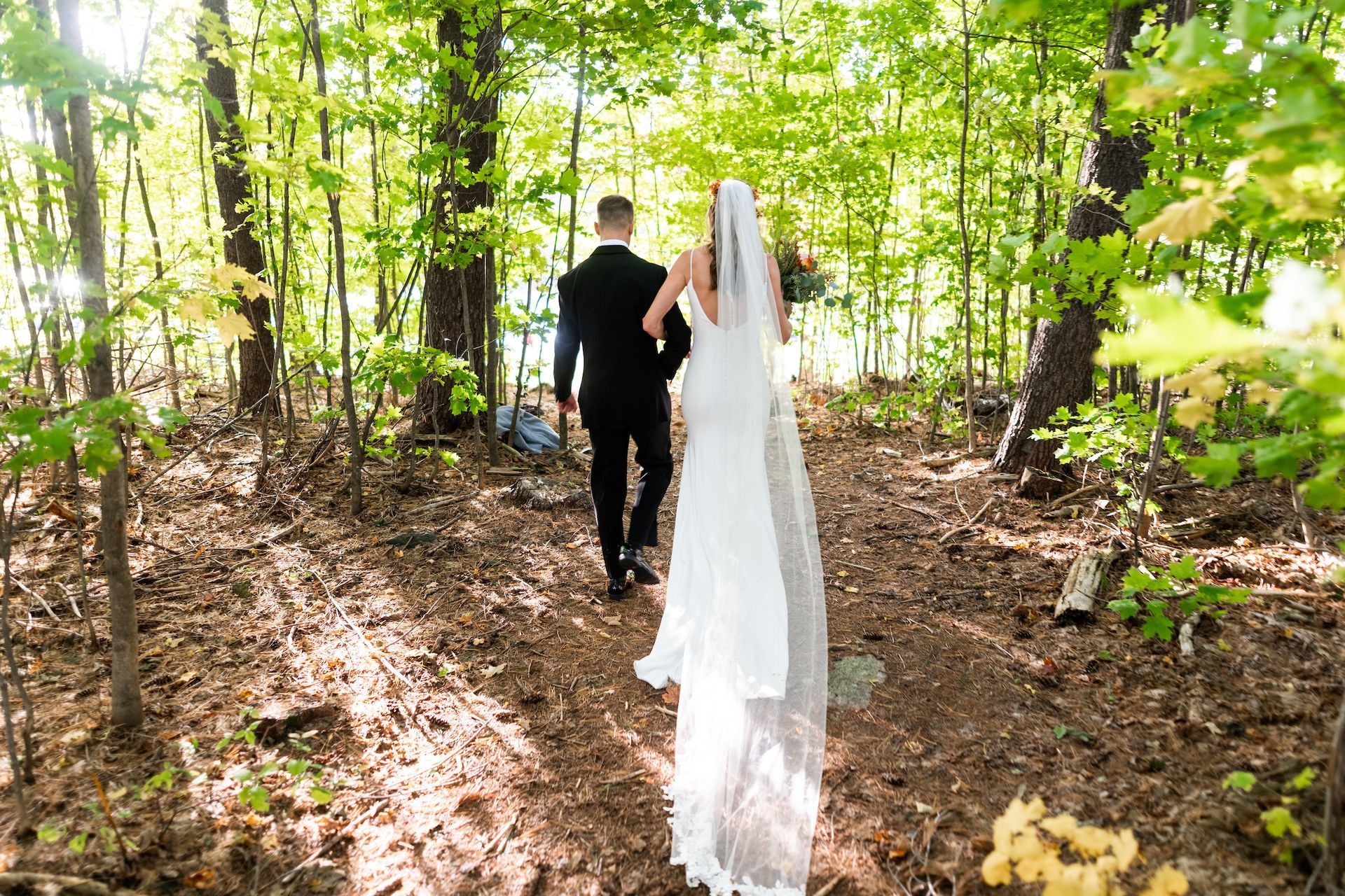 a newlywed couple walking through the forest after