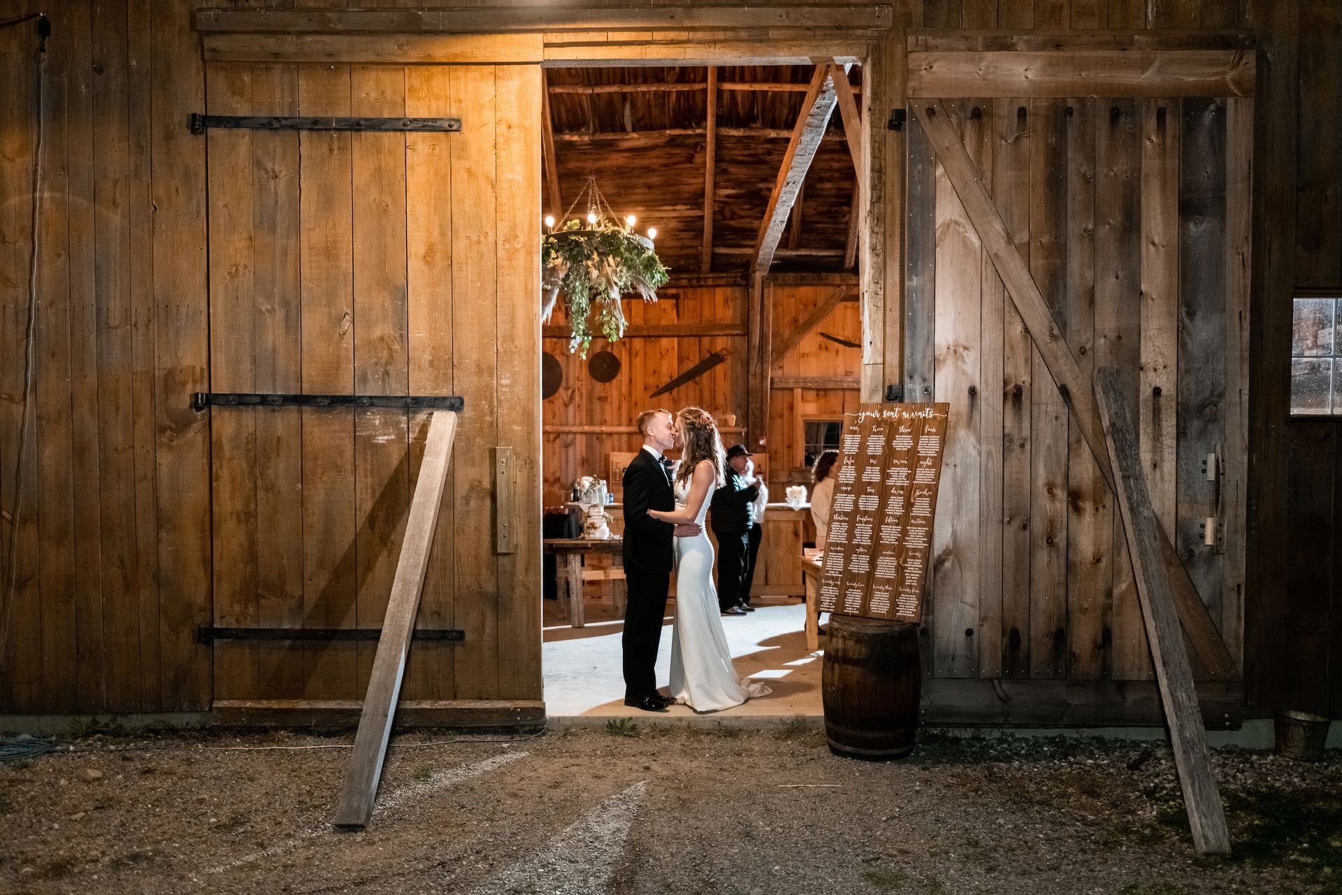 far away shot of a couple in the doorway of the isham family farm events barn during their wedding reception