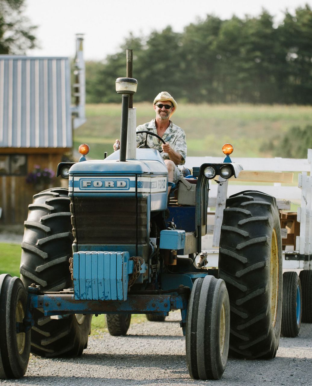 Picture of a man driving a tractor through isham family farm as part of a wedding celebration