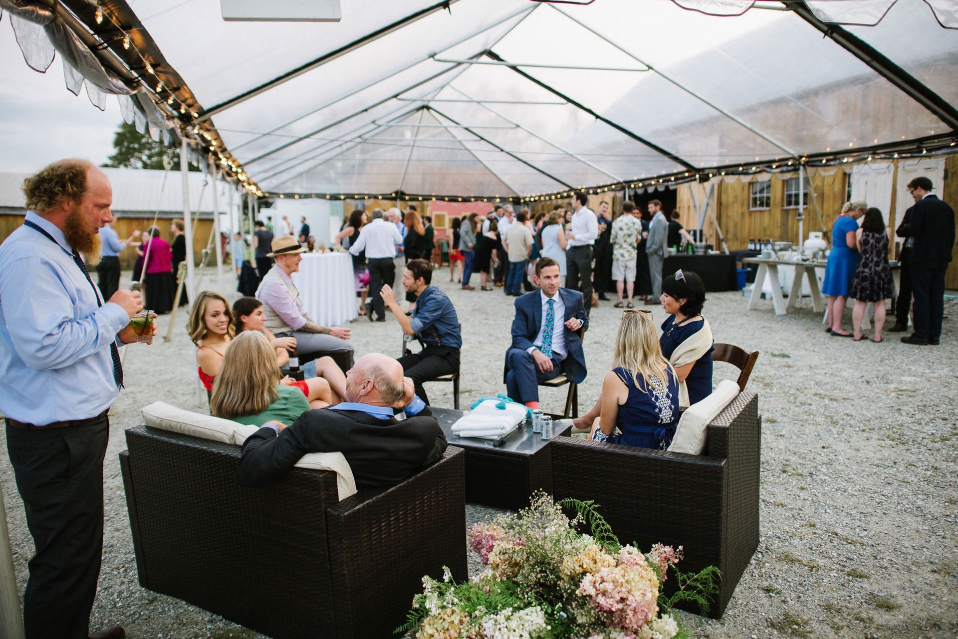 candid shot of wedding attendees enjoying a cocktail hour in the isham family farm outdoor event tents in vt