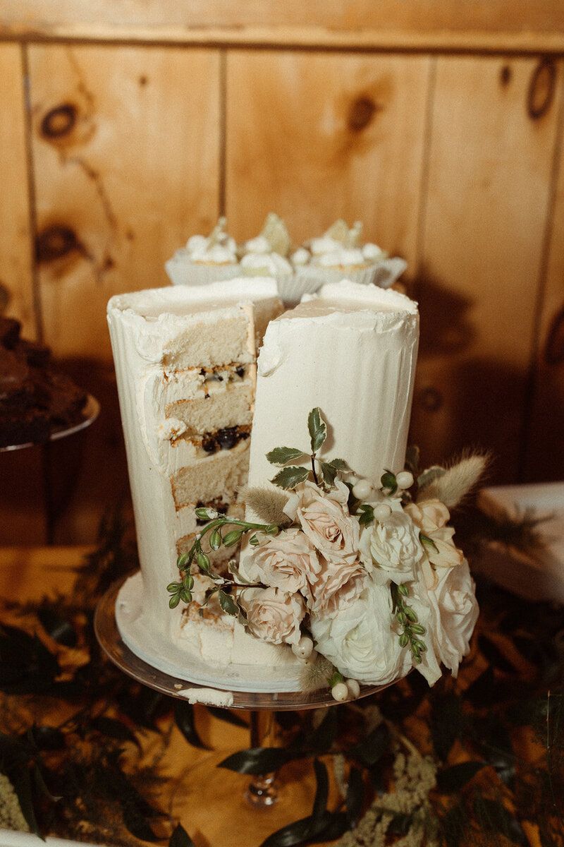close up of a cut into wedding cake inside isham family farm event barn in vermont