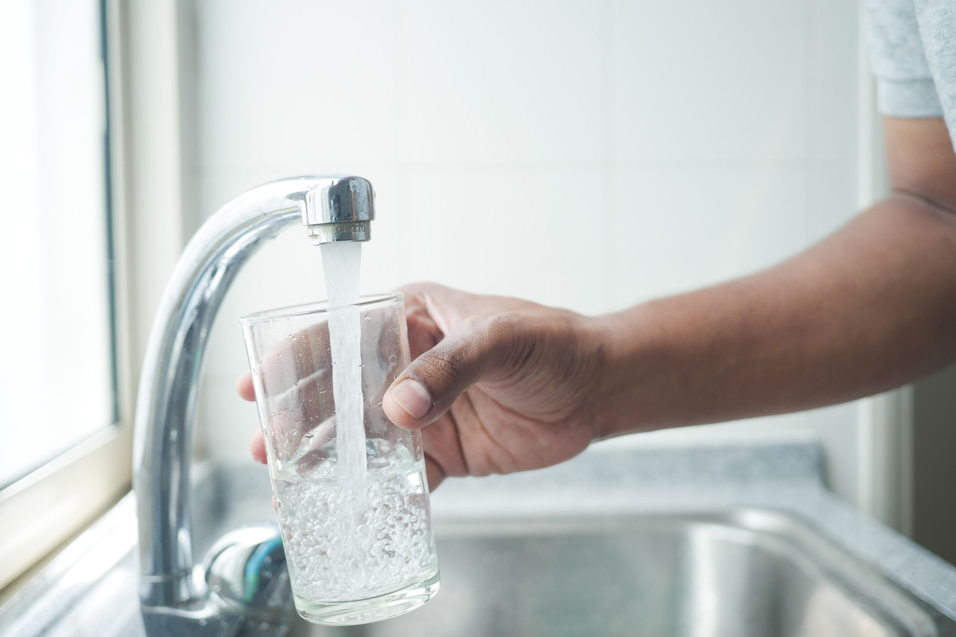 Refilling glass of water from a faucet tap.