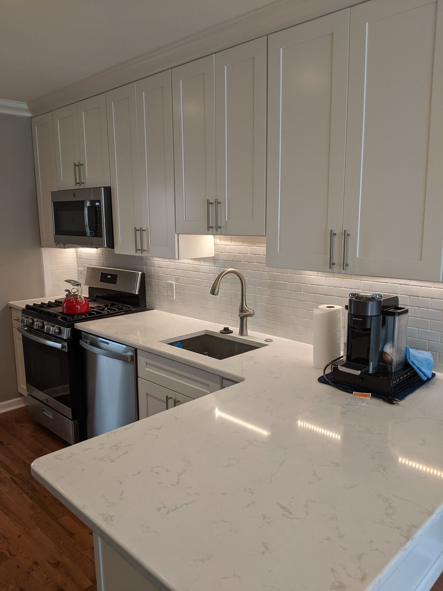 Bright kitchen with white cabinets, stainless steel appliances, and a marble backsplash.