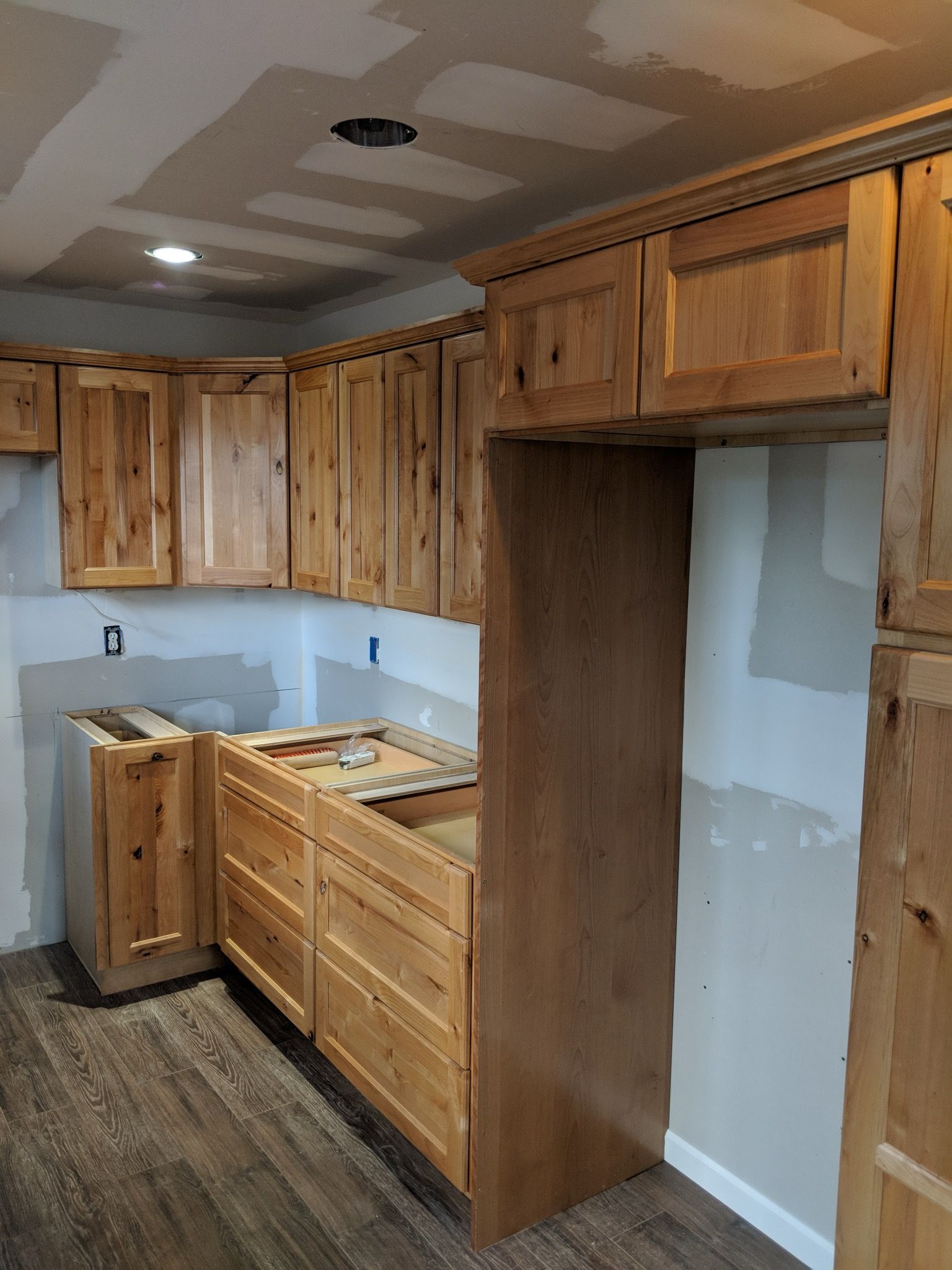 Wooden kitchen cabinets, including uppers and lowers, being installed in a new kitchen.