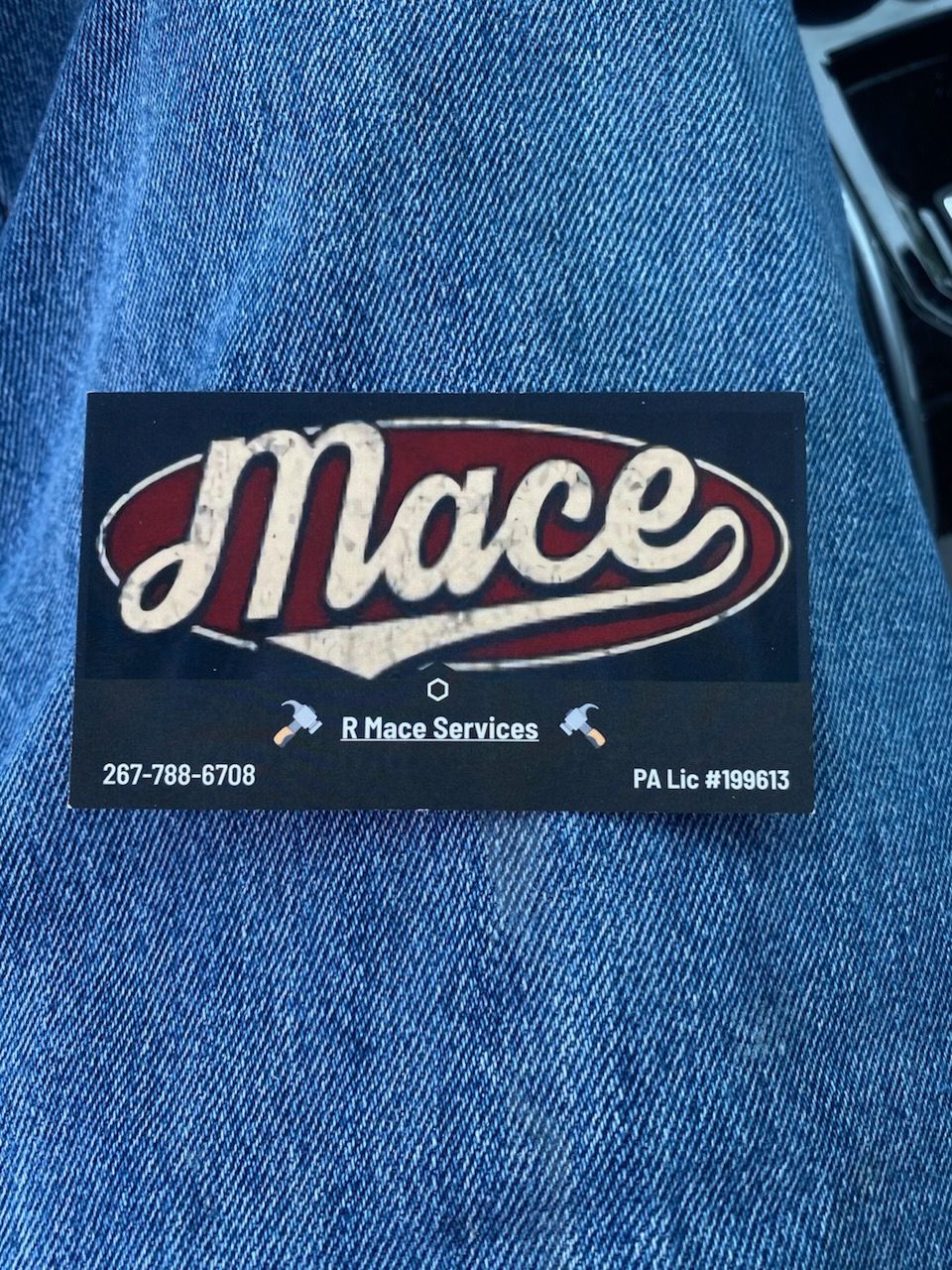 Business card for Mace Services with a red, white, and black logo on a blue jean background.