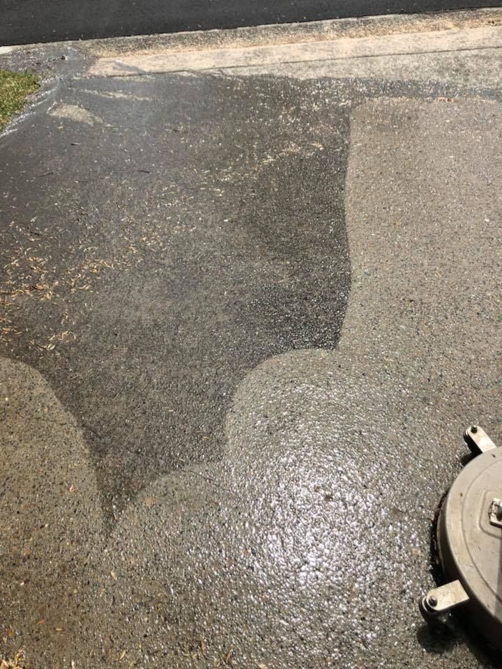 Concrete driveway being cleaned with a pressure washer.