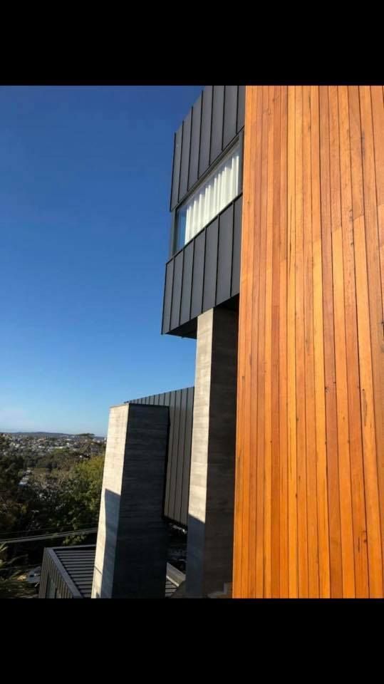 Modern building with wood and concrete facade against a blue sky.
