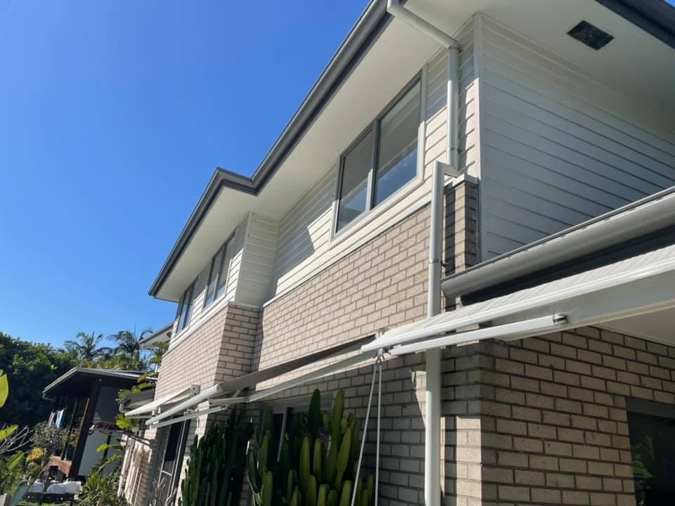 Two-story house with white siding and brick facade under a clear blue sky.