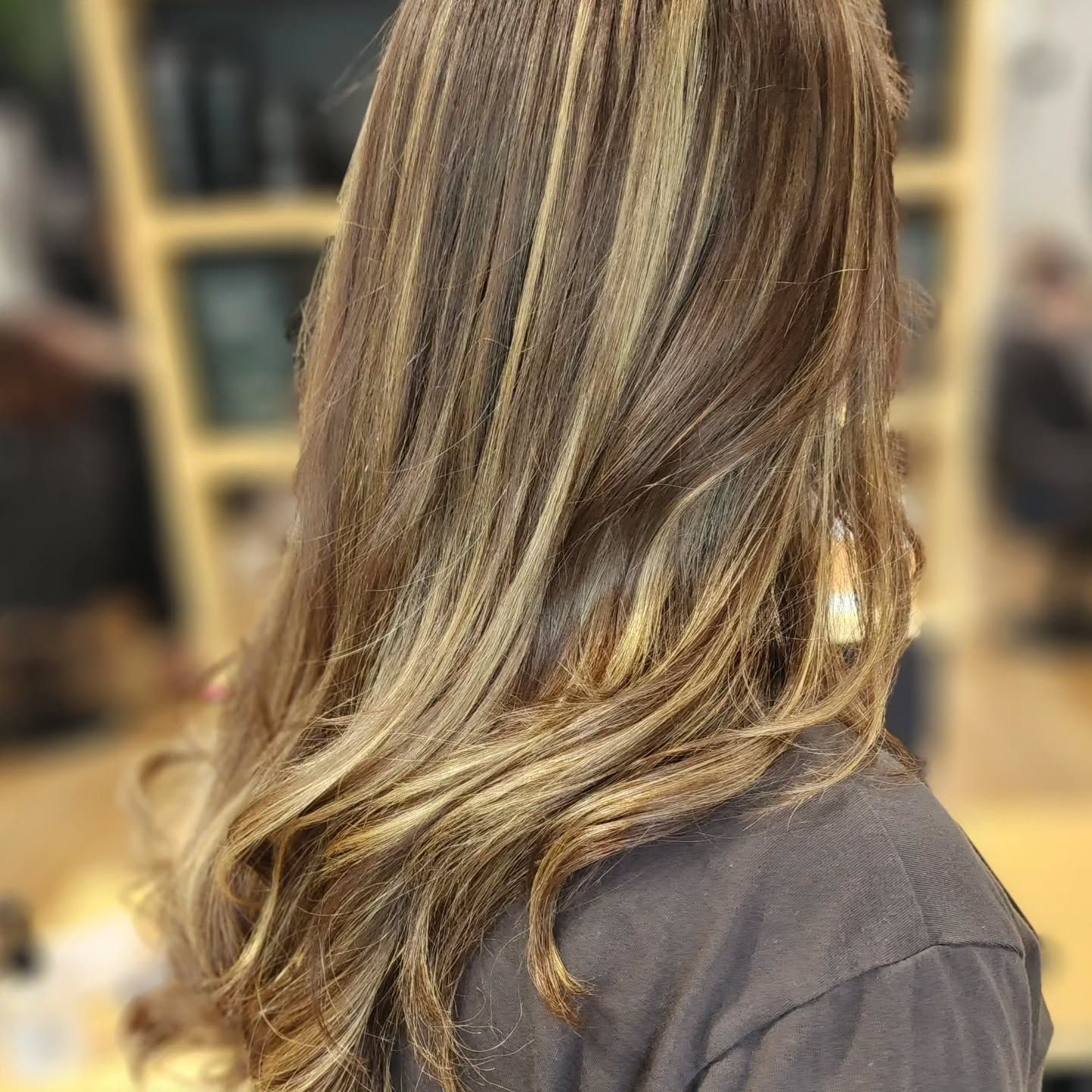 A Woman With Long Brown Hair Is Sitting In A Chair In A Salon — MLB Hair In  Smithfield, QLD
