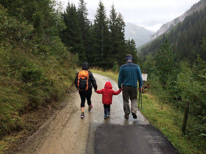 A family is walking down a dirt road holding hands.