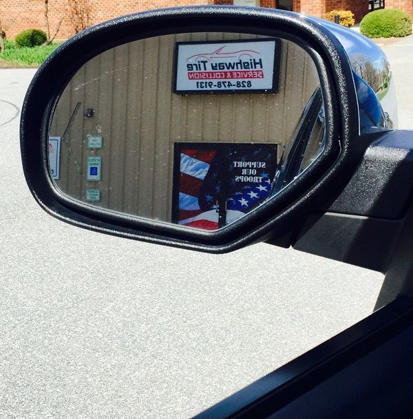 A rear view mirror shows a building with a sign that says u.s. auto tailh