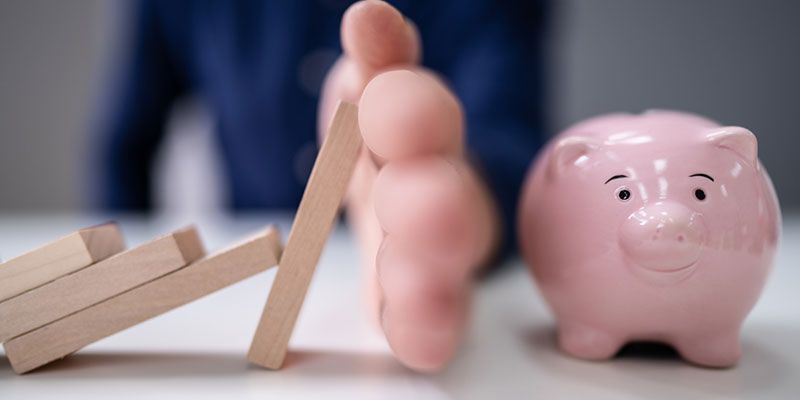 A person 's foot is standing next to a pink piggy bank.