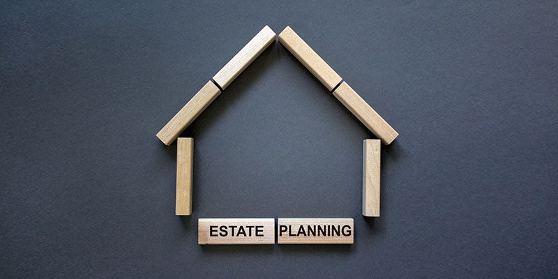 A house made of wooden blocks with the words estate planning written on them.