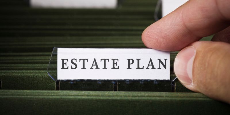 A person is holding a piece of paper that says estate plan.