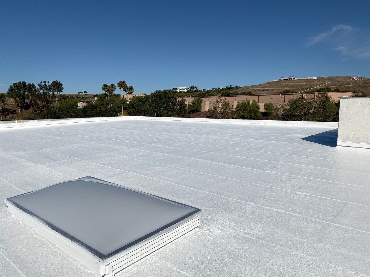 A white roof with a skylight on top of it
