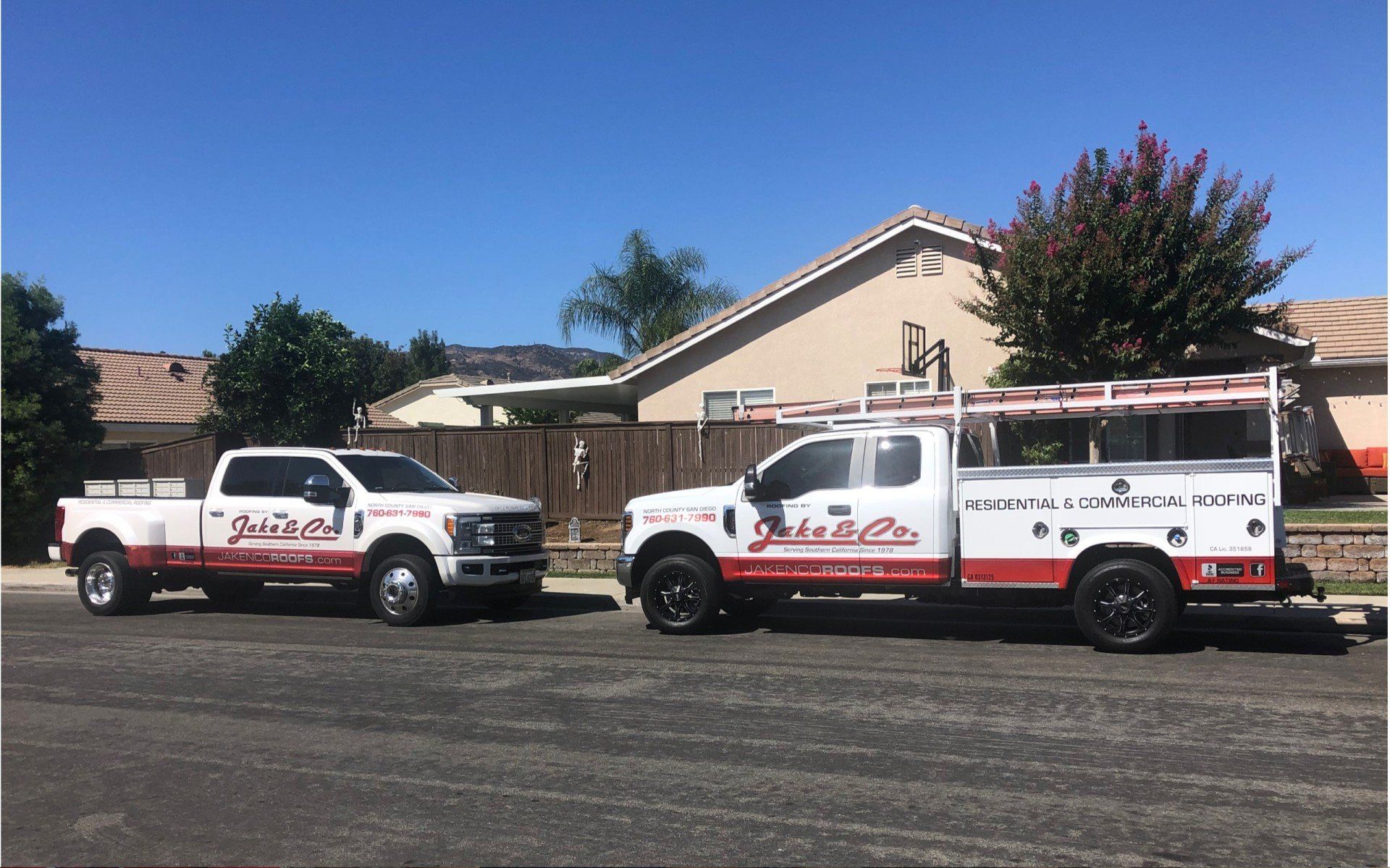 Two trucks are parked on the side of the road in front of a house.