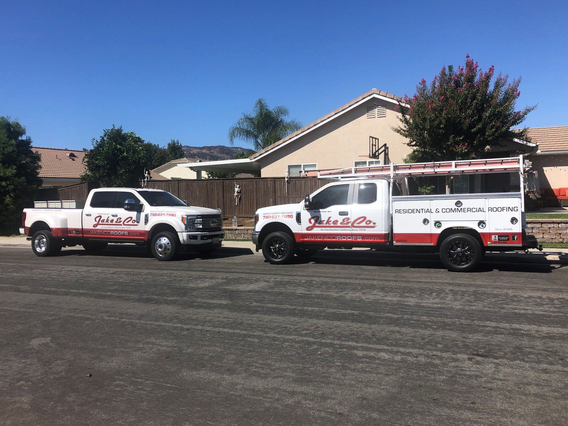 Two trucks are parked on the side of the road in front of a house.