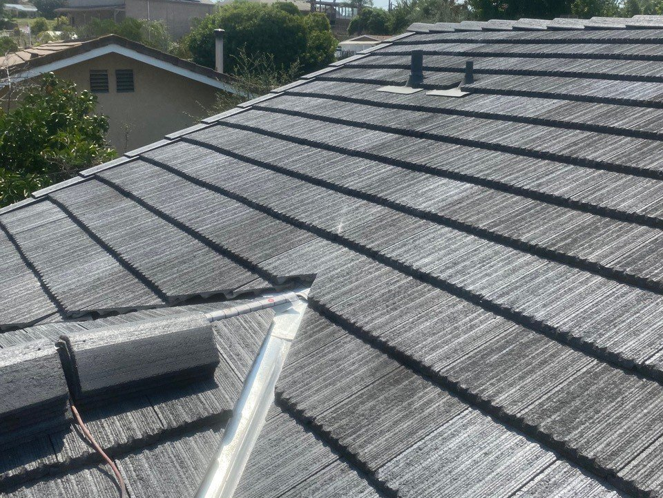 A close up of a roof with a metal pipe on it.
