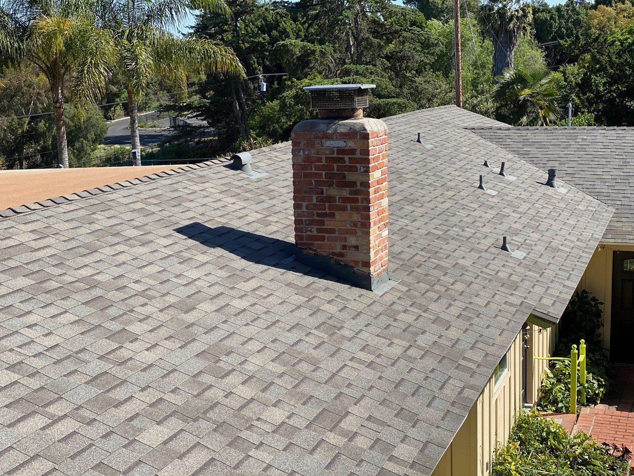 A brick chimney is on the roof of a house.