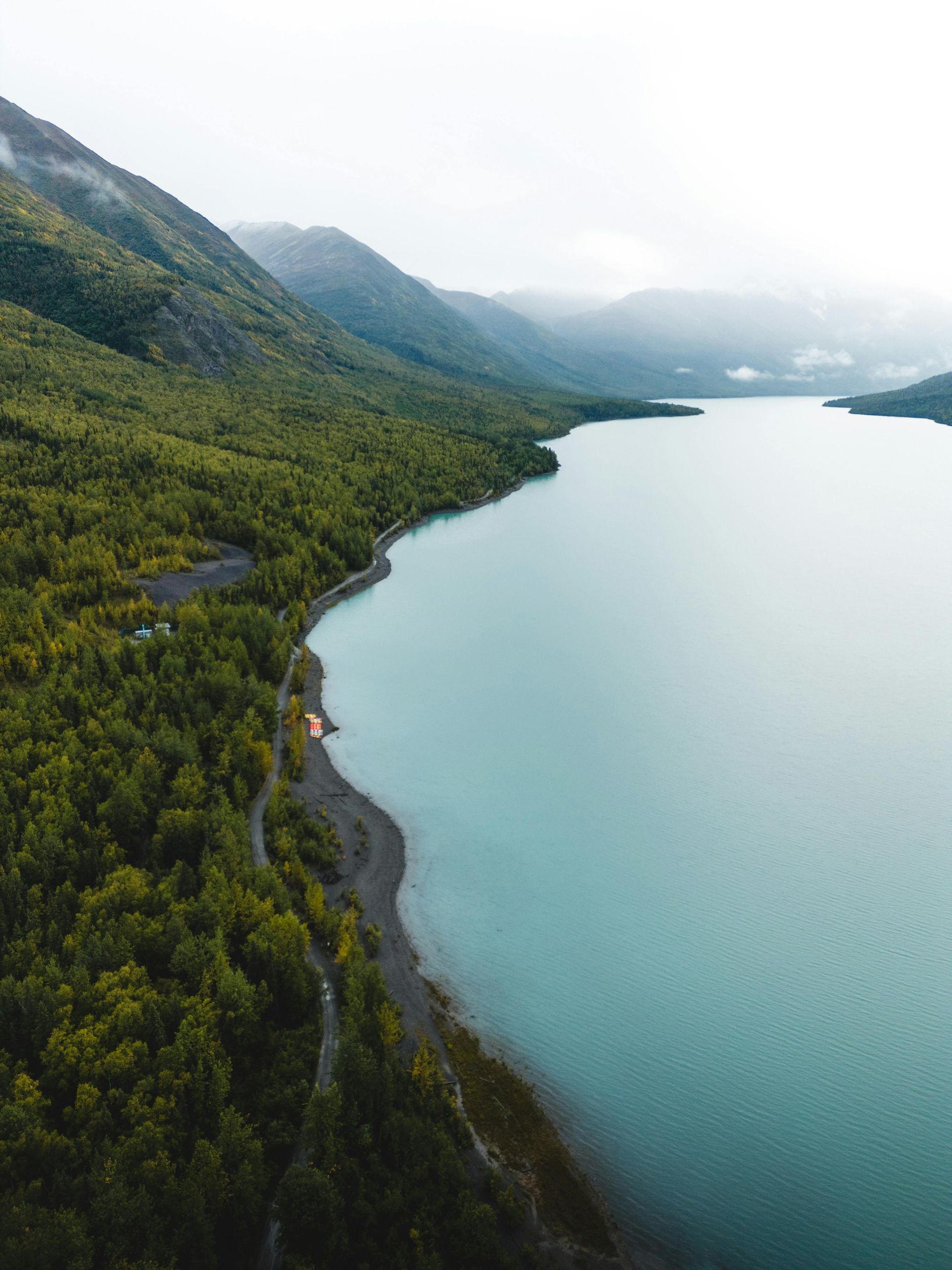 A turquoise lake nestled between lush green mountains under a cloudy sky.