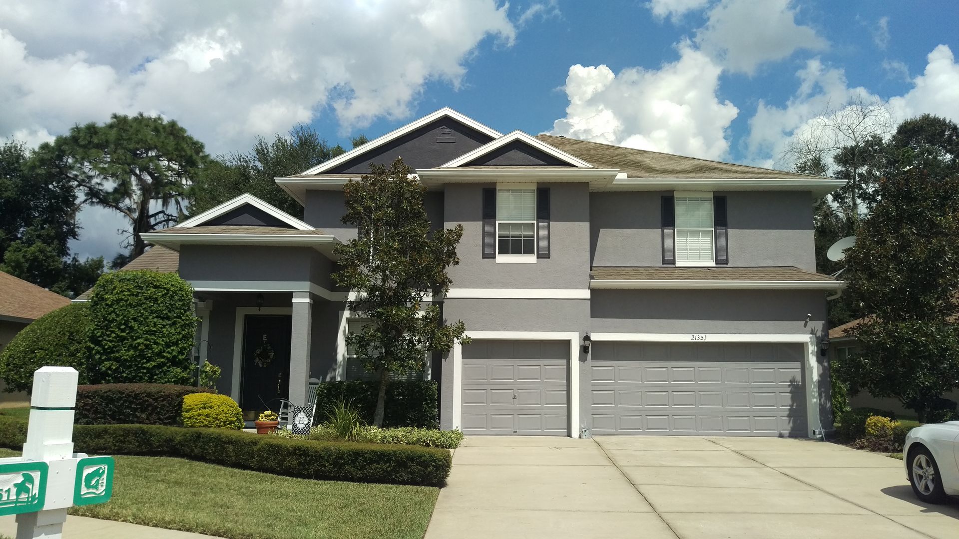 Gray two-story house with two-car garage, blue sky, and landscaping.
