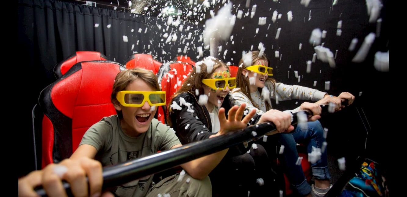 A group of people wearing 3d glasses are riding a roller coaster.