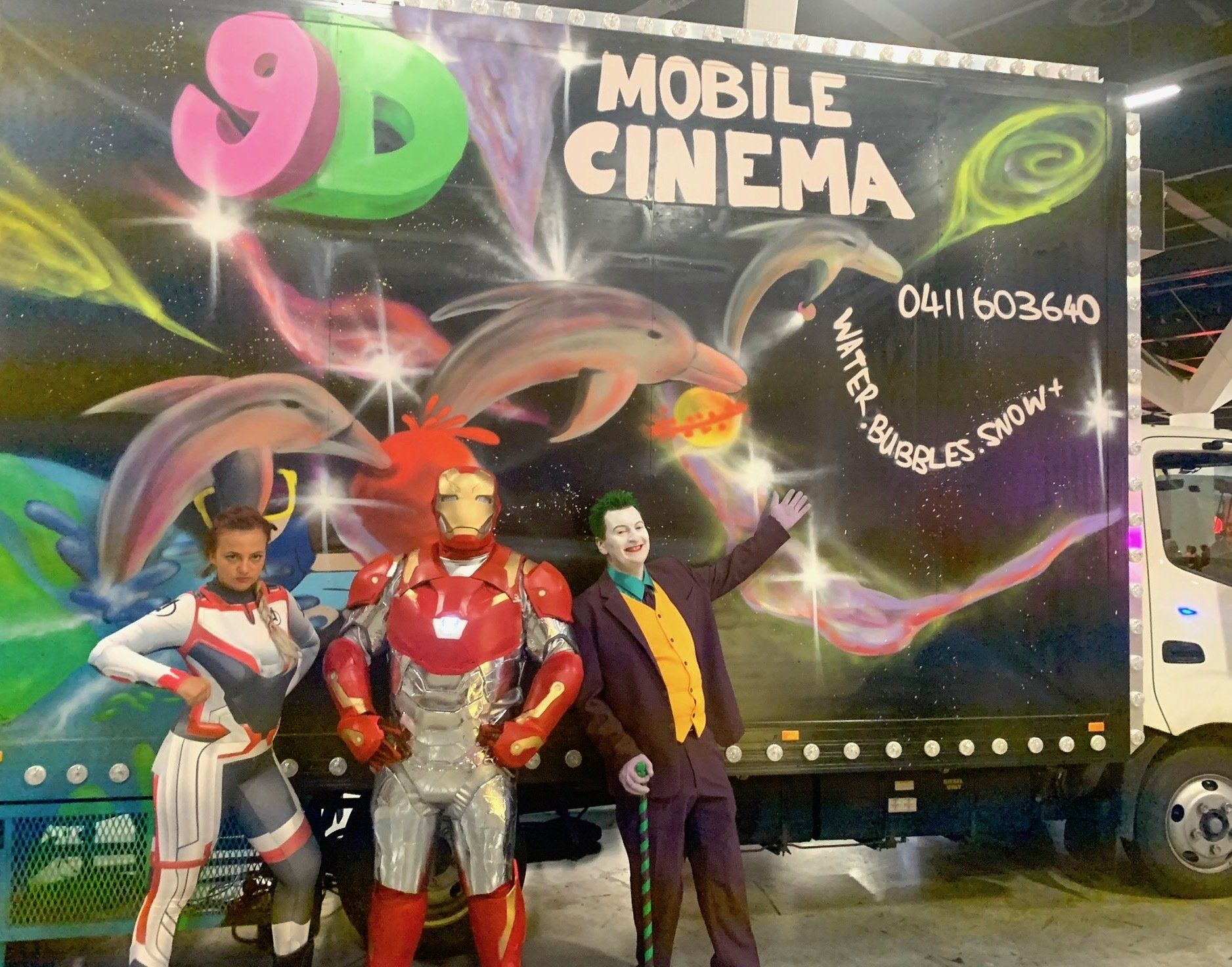 A group of people standing in front of a 9d mobile cinema truck
