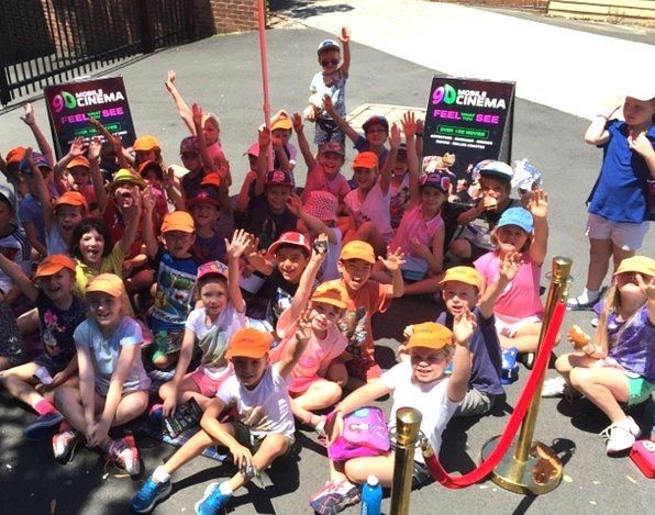 A group of children sitting on the ground with their hands in the air