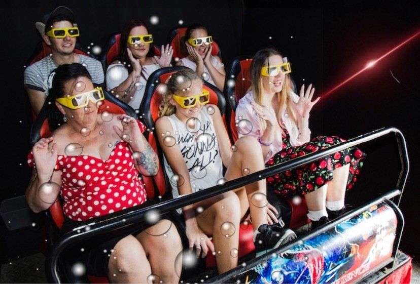 A group of people wearing 3d glasses are riding a roller coaster.