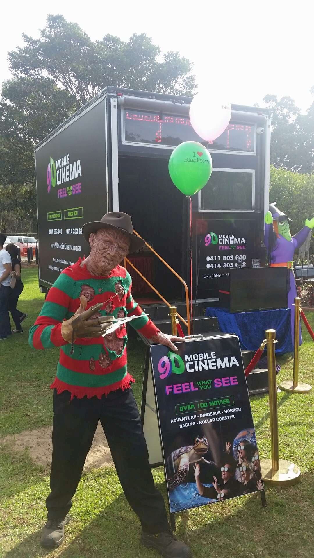 A man dressed as freddy krueger is standing in front of a trailer holding a sign.