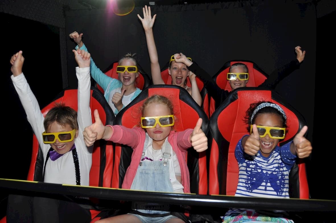 A group of children wearing 3d glasses are giving a thumbs up