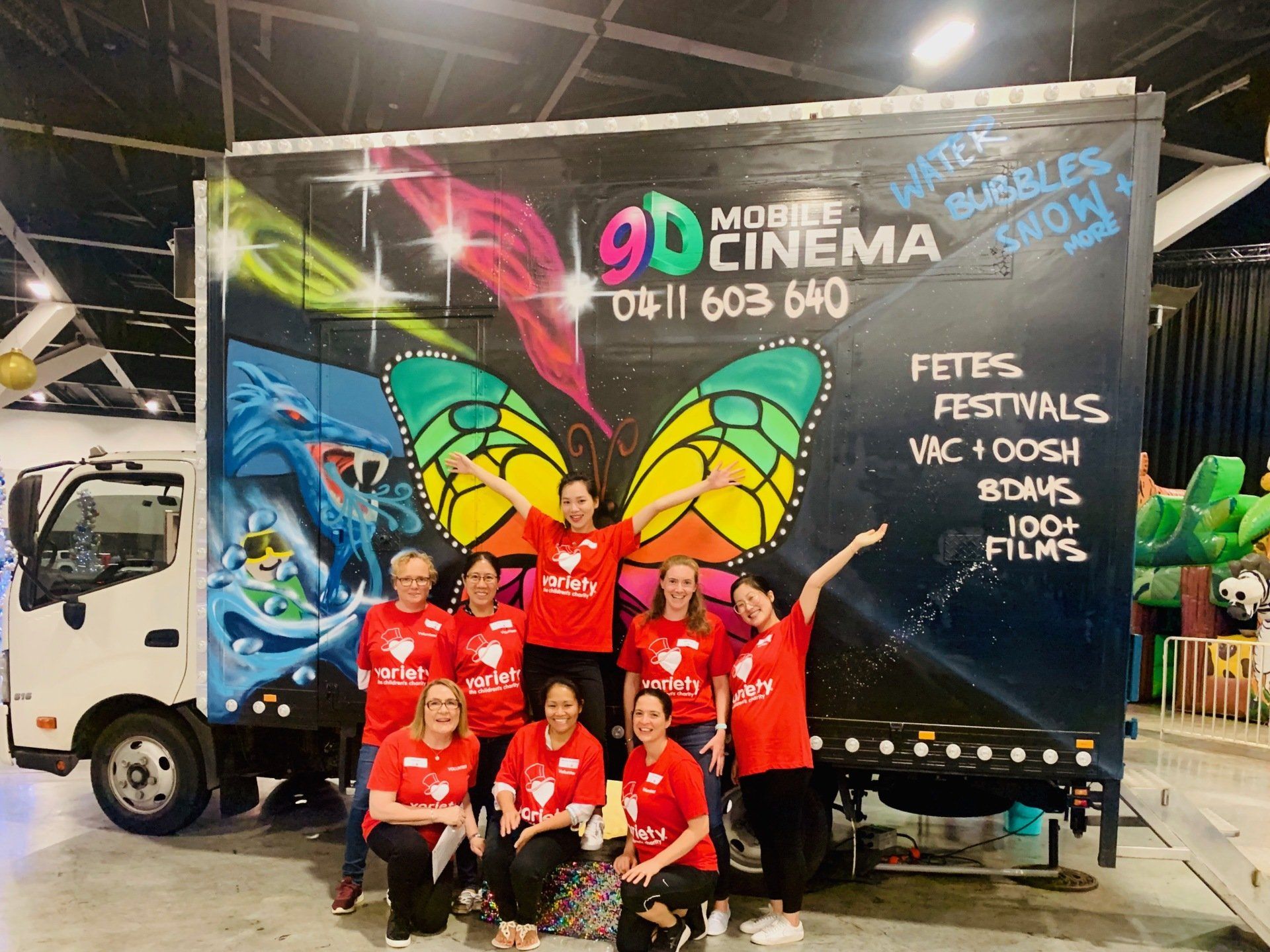 A group of people are posing for a picture in front of a truck.