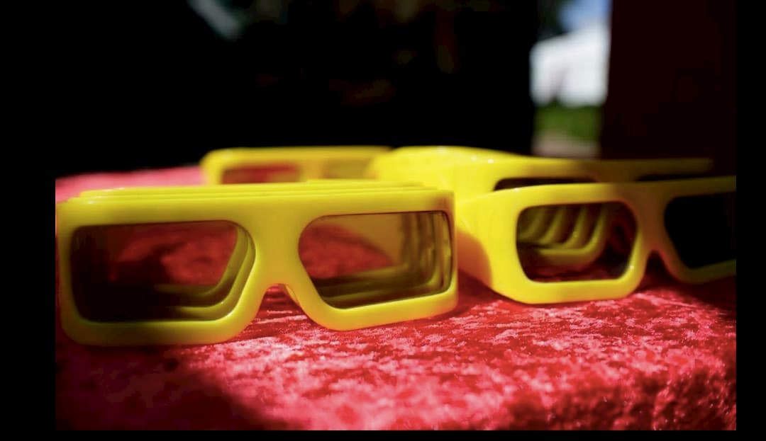 Three yellow glasses are sitting on a red table cloth