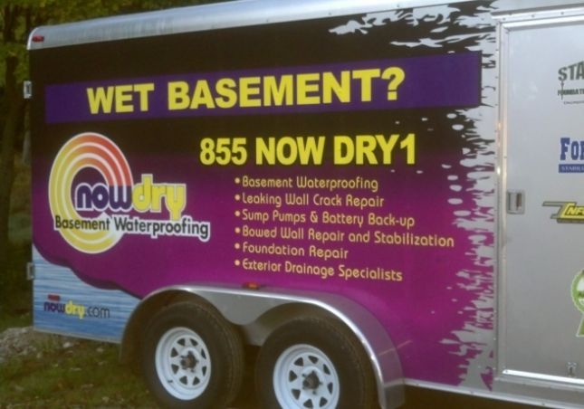 Purple trailer for basement waterproofing service with “WET BASEMENT? 855 NOW DRY1” text.